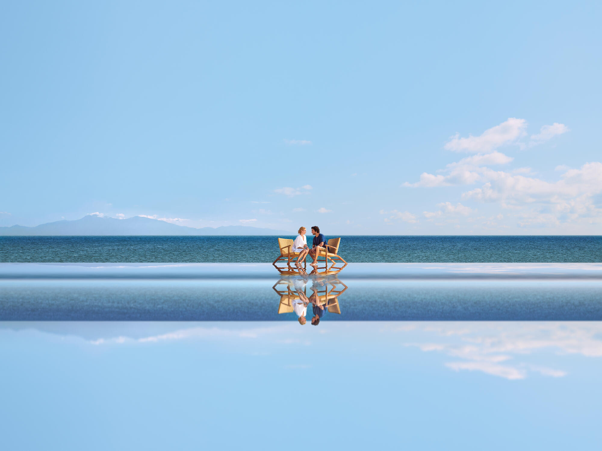 Seuls au monde - couple avec chaises sur l'eau
